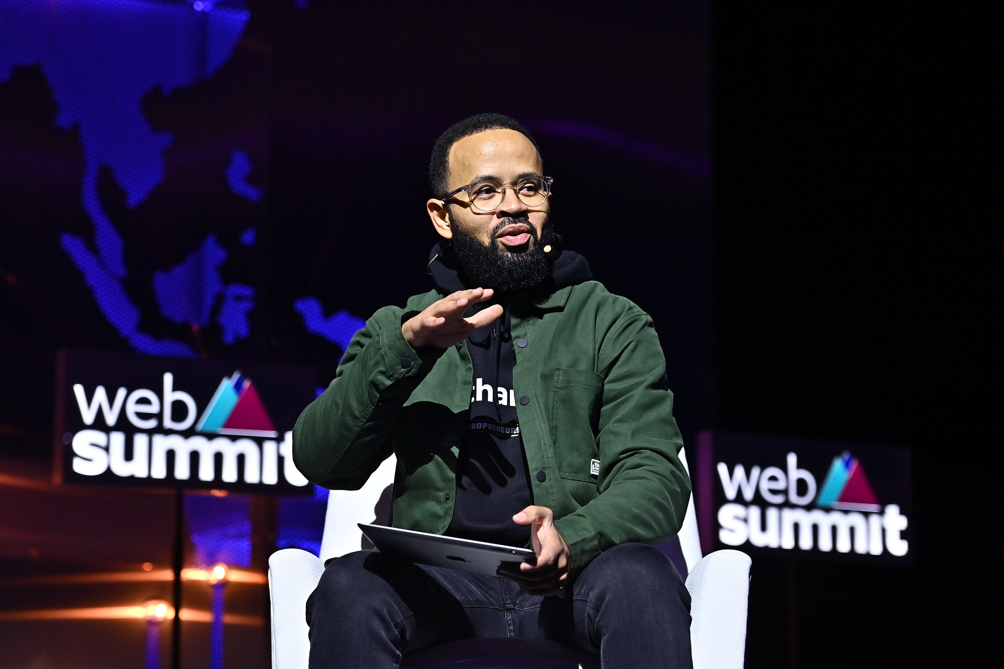 Photograph of a person (Fernando Cabral, managing director/managing partner of FS-360/Djassi Africa) speaking on stage at Web Summit. They are sitting on a chair and holding what appears to be notes in their hand.