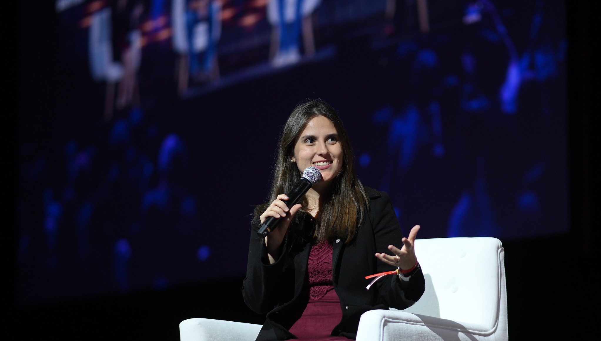 A photo of a person (Mariana Vasconcelos, co-founder and CEO of Agrosmart) speaking on stage at Web Summit. The person is sitting on a chair and holding a microphone.