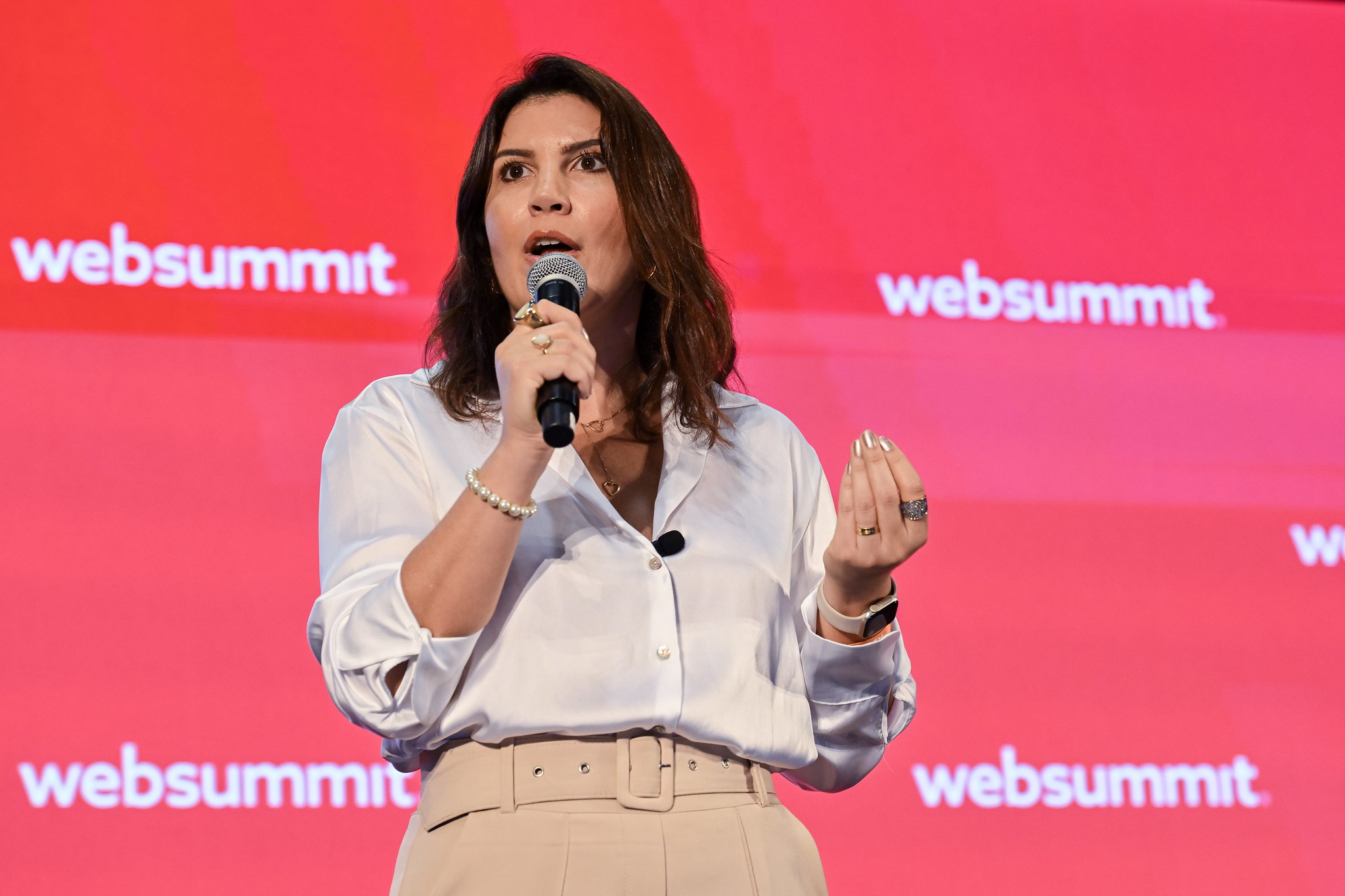 A photo of a person, Maria Luisa Fontes, CEO of Fusion Clinic, speaking onstage at Web Summit 2023. The person is holding a microphone in their hand. They are standing against a plain coloured background with the Web Summit logo visible.