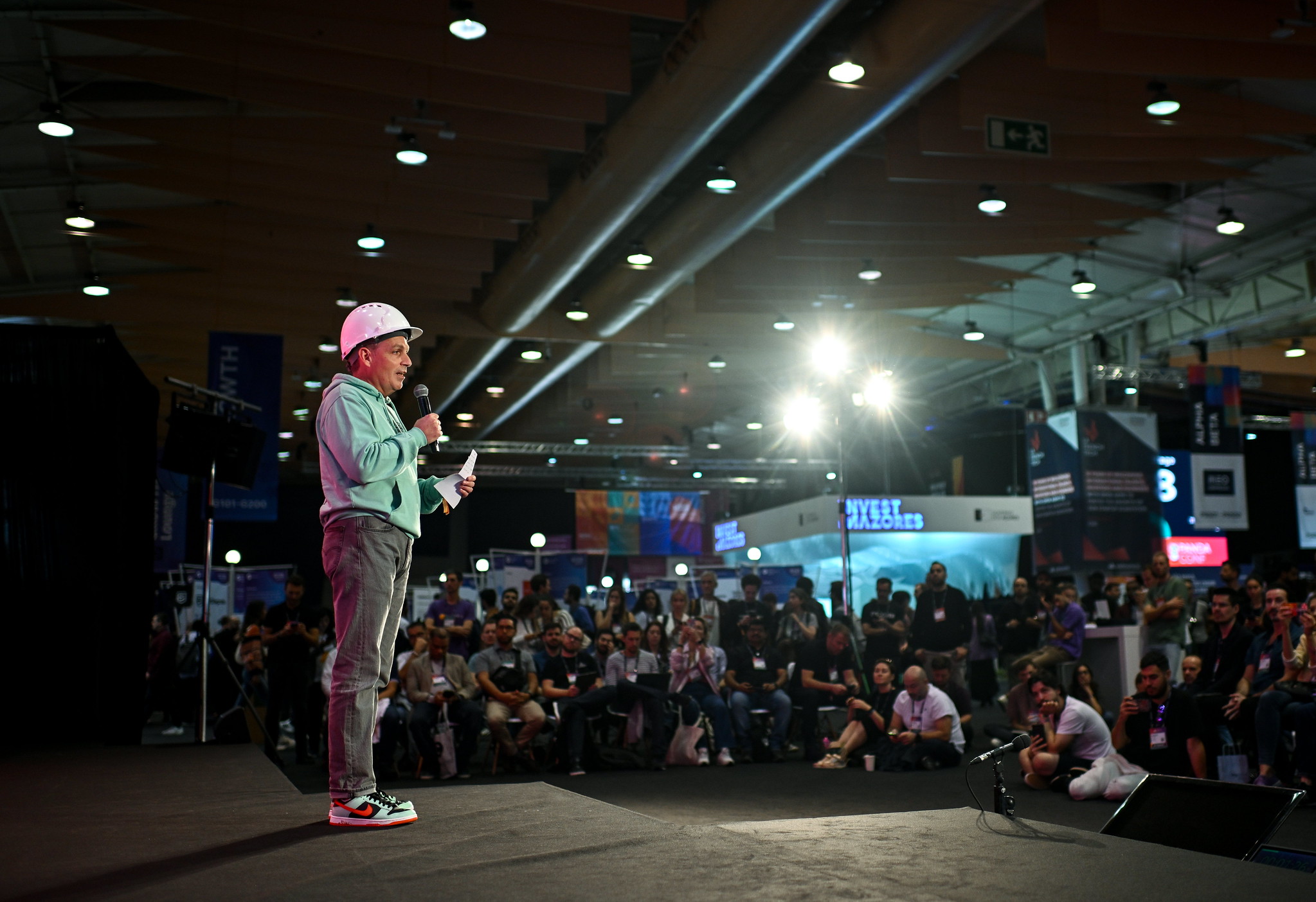 A photo of a person, Mathew Norbury, CEO of FC Laboratories, standing onstage at Web Summit. They are holding a microphone and appear to be speaking. There is a large crowd of people that appear to be watching this person.