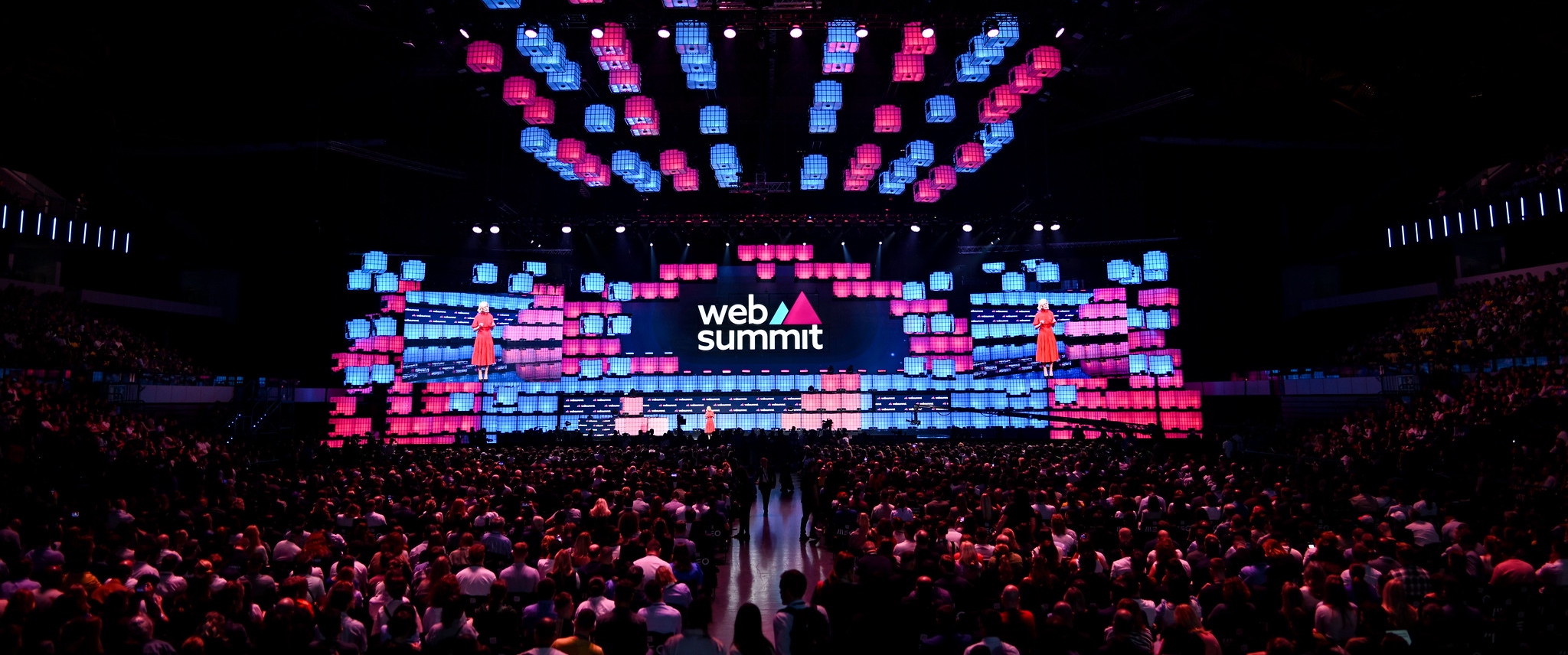 A large stage viewed from the back of an auditorium. A seated audience faces the stage. This is Opening Night at Web Summit 2023.