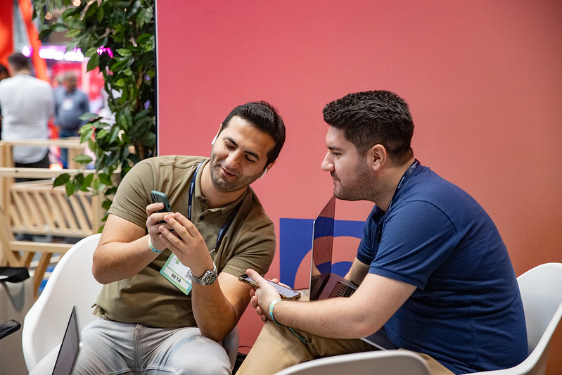 Two men look excitedly at a phone screen in the Startup lounge at Web Summit Qatar.