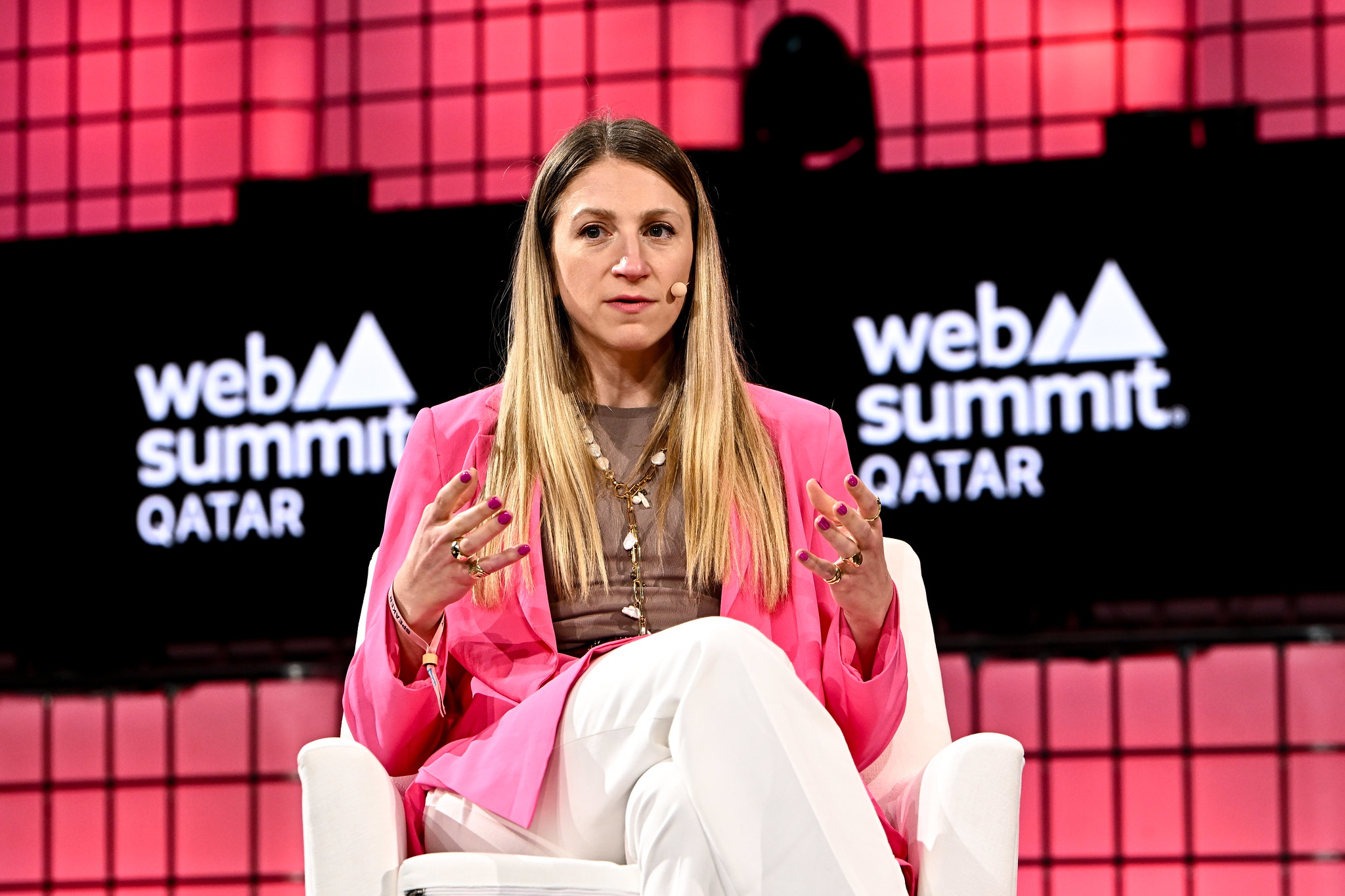 A photo of Aspa Lekka, co-founder of JOKR and executive in residence at Alpine Investors, on Centre Stage during Day 1 of Web Summit Qatar. Aspa is sitting on a chair and gesturing with her hands. She is wearing a headset microphone. The Web Summit Qatar logo is visible in the background.